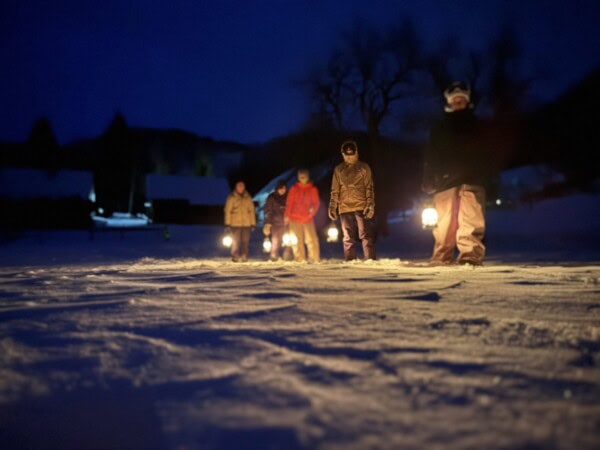 Night lantern snowshoe lantern walk in Bohinj, Slovenia illuminated by lanterns highlighting winter landscape and outdoor adventure.